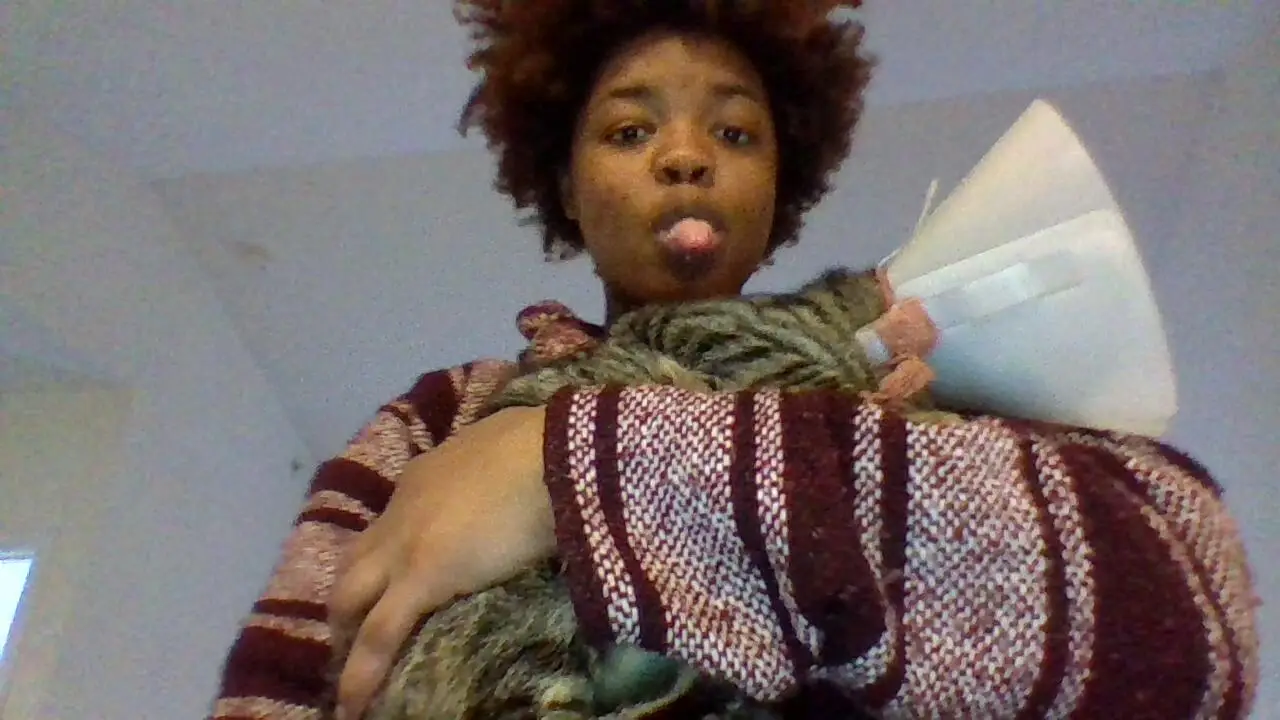 Amari carrying a fluffy cat wearing a recovery cone after a vet visit