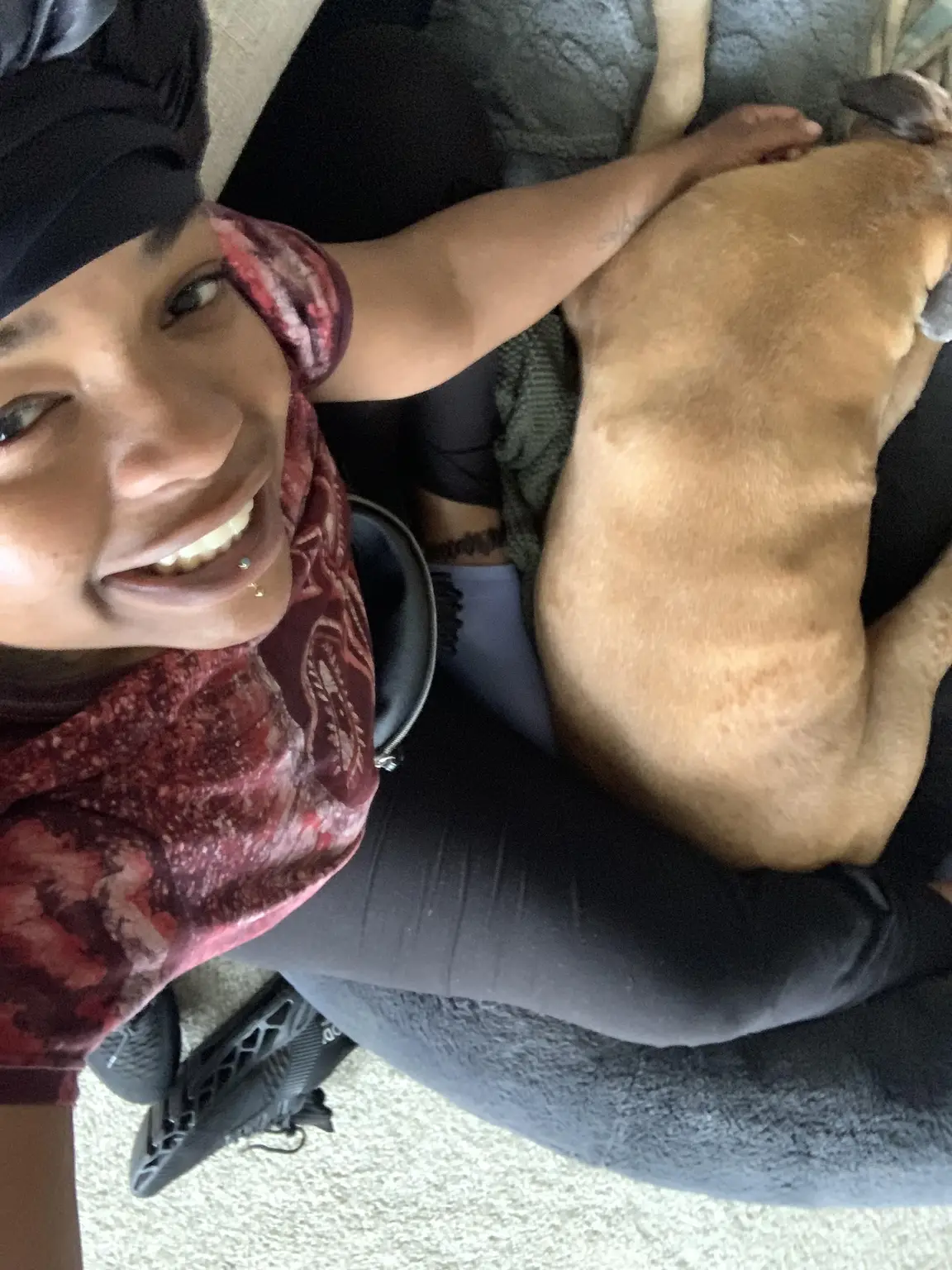 Amari smiling while gently massaging a tan dog with joint problems